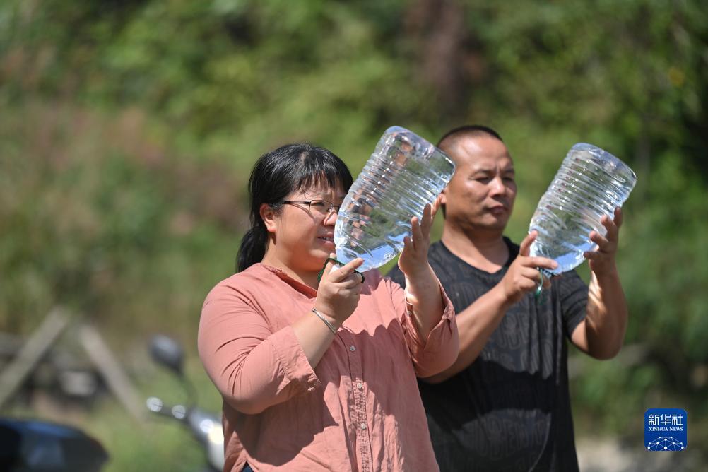 楊寧（左）在查看村民剛剛采集的水樣，為山泉水引水工程做準備（10月8日攝）。新華社記者 黃孝邦 攝